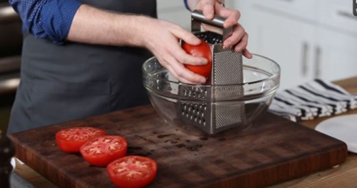 Man Rubs Raw Tomato Against A Cheese Grater To Make A Classic Sauce